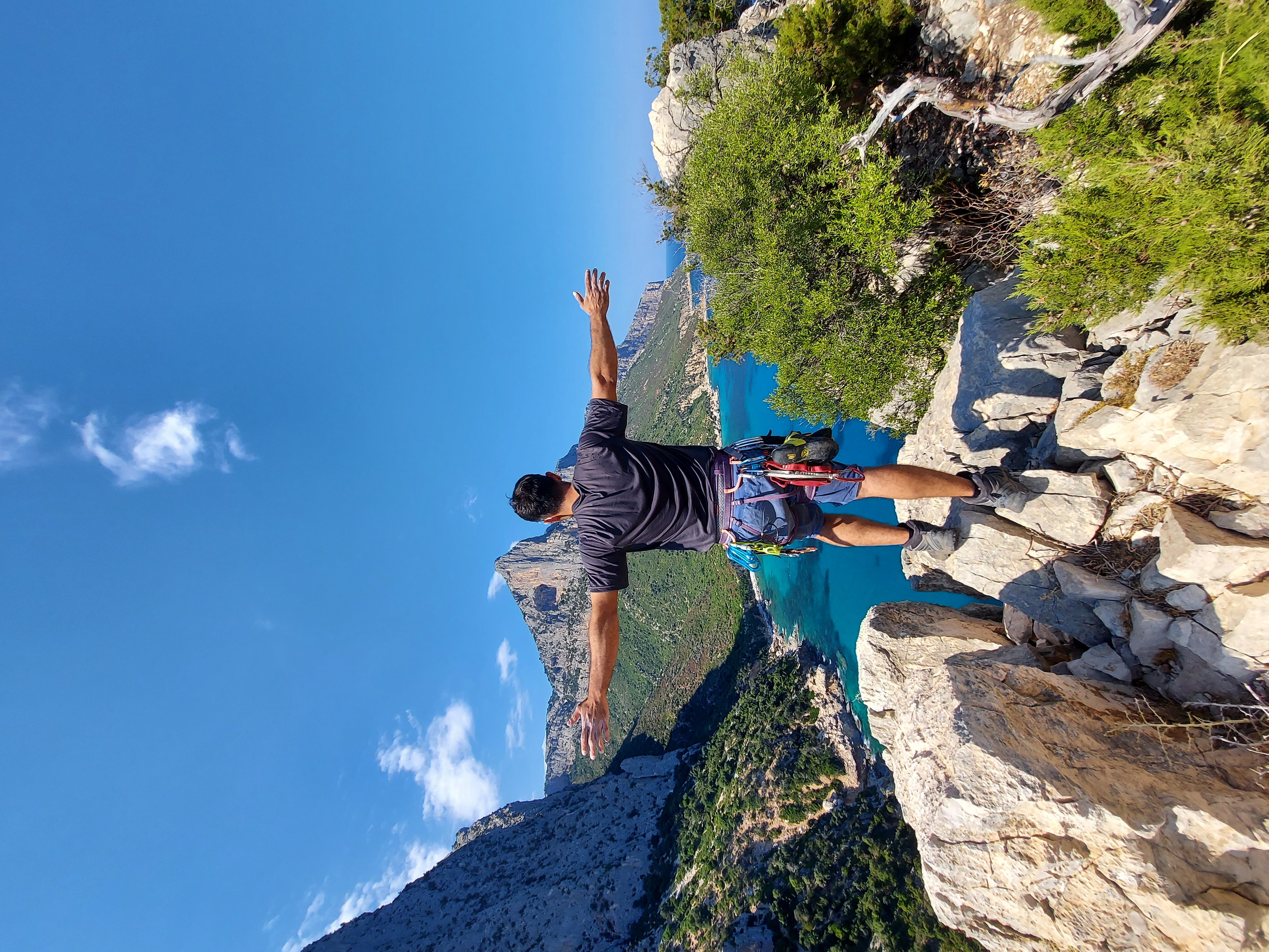 Jesus Marini Parissi standing in climbing equipment above a mountainous coastline